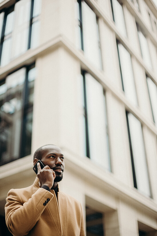 man talking on cellphone with blurred building in background