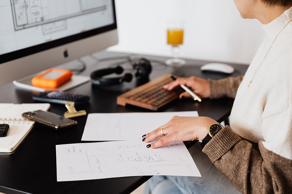 A person's hands, as seen from the side, reviewing documents at their desk